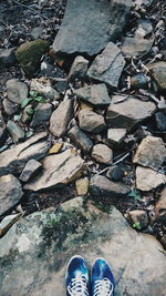 Low section of man standing on pebbles