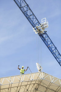 Low angle view of successful worker standing on roof at construction site