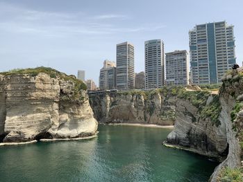 Buildings by sea against sky