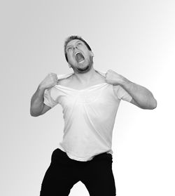 Distraught man tearing t-shirt against white background