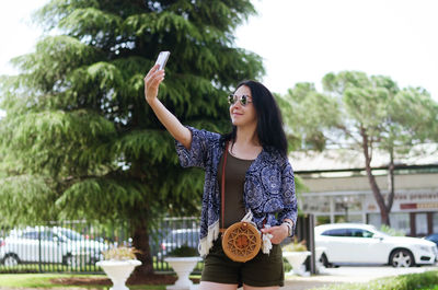 Young happy business woman relaxing in city, park. using phone. selfie. technology. summer vacation