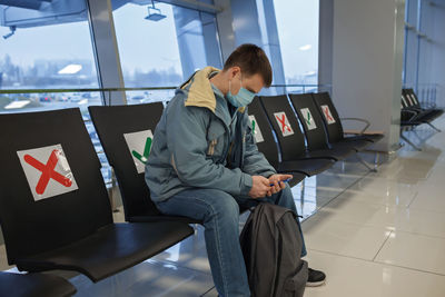 Man wearing mask sitting at airport lounge