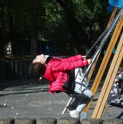 Girl playing on swing in playground