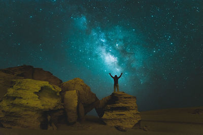 Rear view of man standing on rock against star field