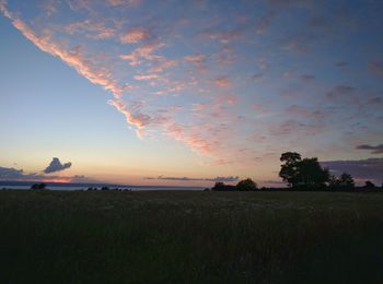 Scenic view of silhouette field against sky at sunset