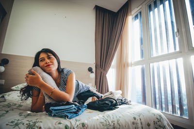 Smiling young woman lying on bed at home