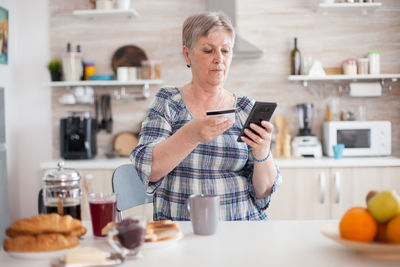 Midsection of man using laptop on table at home