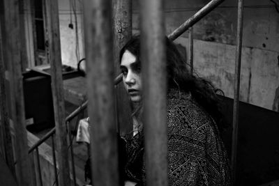 Portrait of young woman looking through window in abandoned building