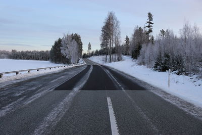 Empty road along snow covered landscape