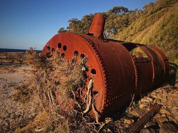 Old rusty wheel on field against sky