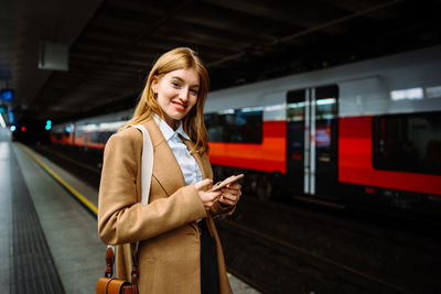 Portrait of young woman standing in train