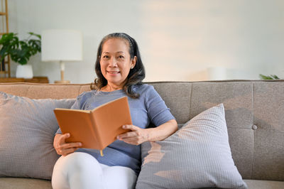 Young woman using laptop while sitting on sofa at home