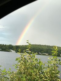 Scenic view of rainbow over lake against sky