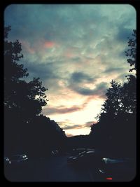 Cars on road against cloudy sky