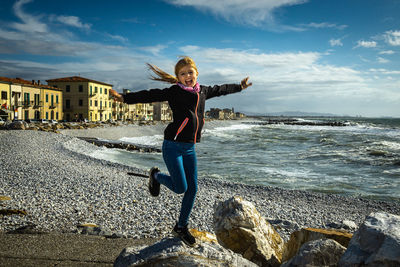 Full length of man standing on rock at sea shore against sky