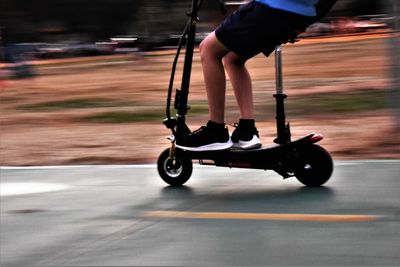 Low section of child riding electric push scooter on road at city