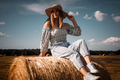 A beautiful young ukrainian woman sits on a hay bale
