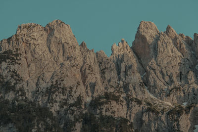 Low angle view of rocky mountains against clear sky