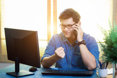 Young man using mobile phone while sitting on table