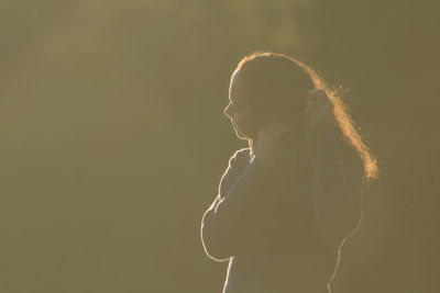 Side view of woman looking down against gray background