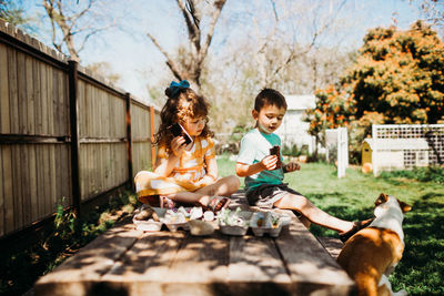 Preschool age siblings sitting on picnic table eating icecream