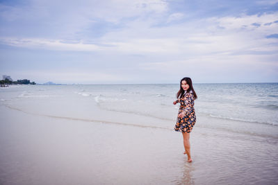 Woman standing on beach against sky