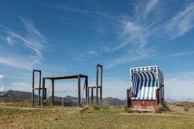 Hooded beach chair on field against sky