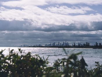 View of buildings in sea against cloudy sky