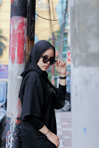 Portrait of young woman wearing sunglasses standing outdoors