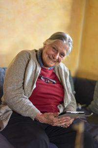 Portrait of smiling senior woman holding digital tablet at home