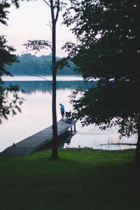 Man on field by lake against sky