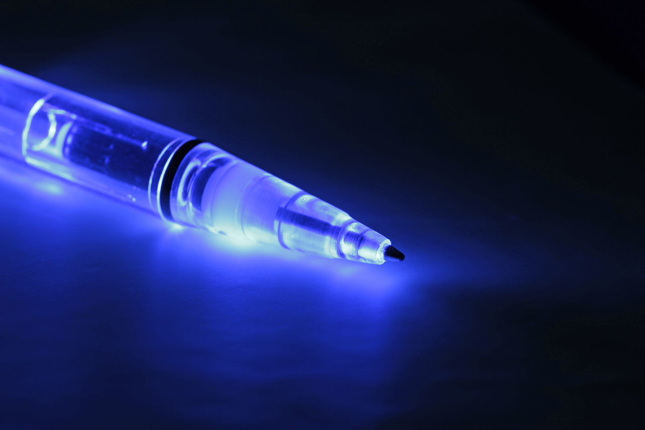 CLOSE-UP OF ILLUMINATED BLUE GLASS ON TABLE