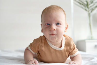 Portrait of cute baby boy lying on bed at home