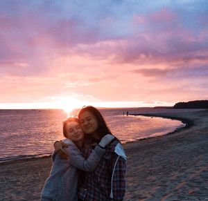 Woman standing at beach against sky during sunset