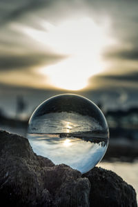 Close-up of crystal ball on rock against sky