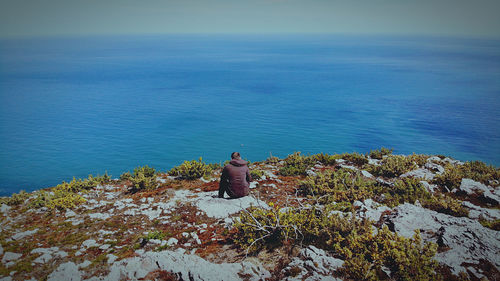 High angle view of man sitting on sea against sky