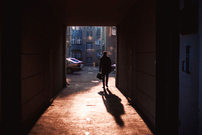 Rear view of silhouette man walking at doorway during sunset