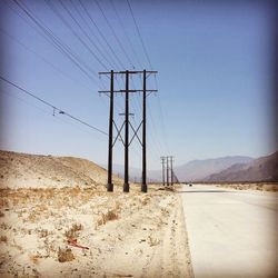 Electricity pylon on desert against clear sky