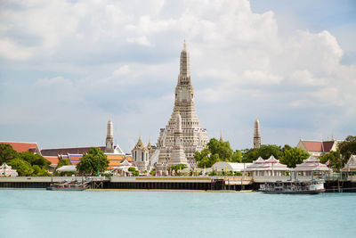 Buildings at waterfront against cloudy sky