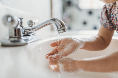 Close up view of young child washing hands with soap in sink