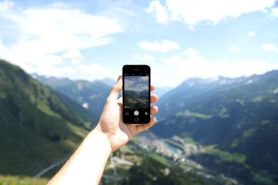 Cropped image of man photographing through smart phone