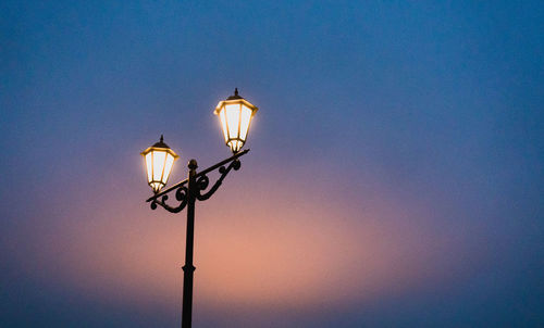 Low angle view of illuminated street light against clear sky at dusk