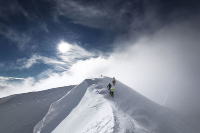 Low angle view of people skiing on snow covered mountain