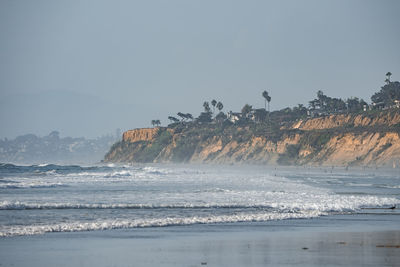 Scenic view of waves splashing in sea by rocky cliff at san diego