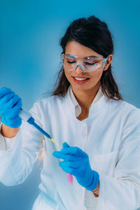 Student in white coat, working in research laboratory using micro pipette and test tube