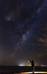 Man holding lantern against night sky