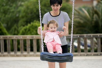 Mother swinging cute baby girl at park