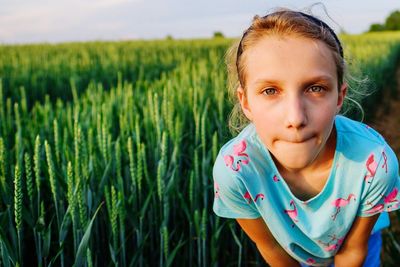 Portrait of girl bending against crops at farm