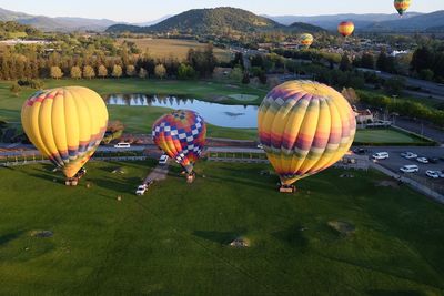 Colorful hot air balloons on field against mountain