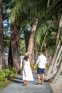 Rear view of woman walking on palm trees